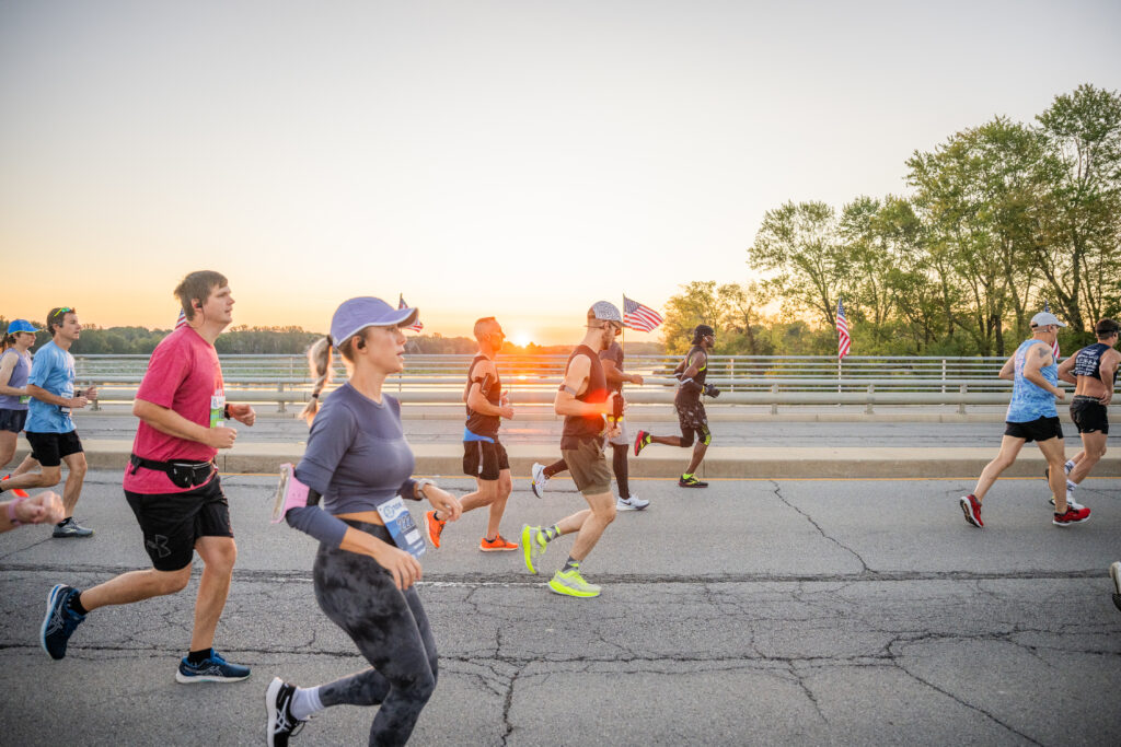 sunrise over geist reservoir with group of runners in geist half marathon