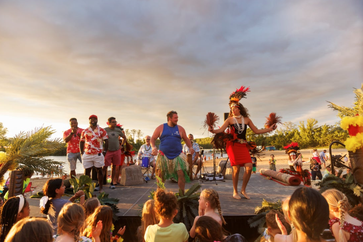 fishers-luau-2024-011 dancers in hula outfits on the beach at geist waterfront park with crowd of people cheering