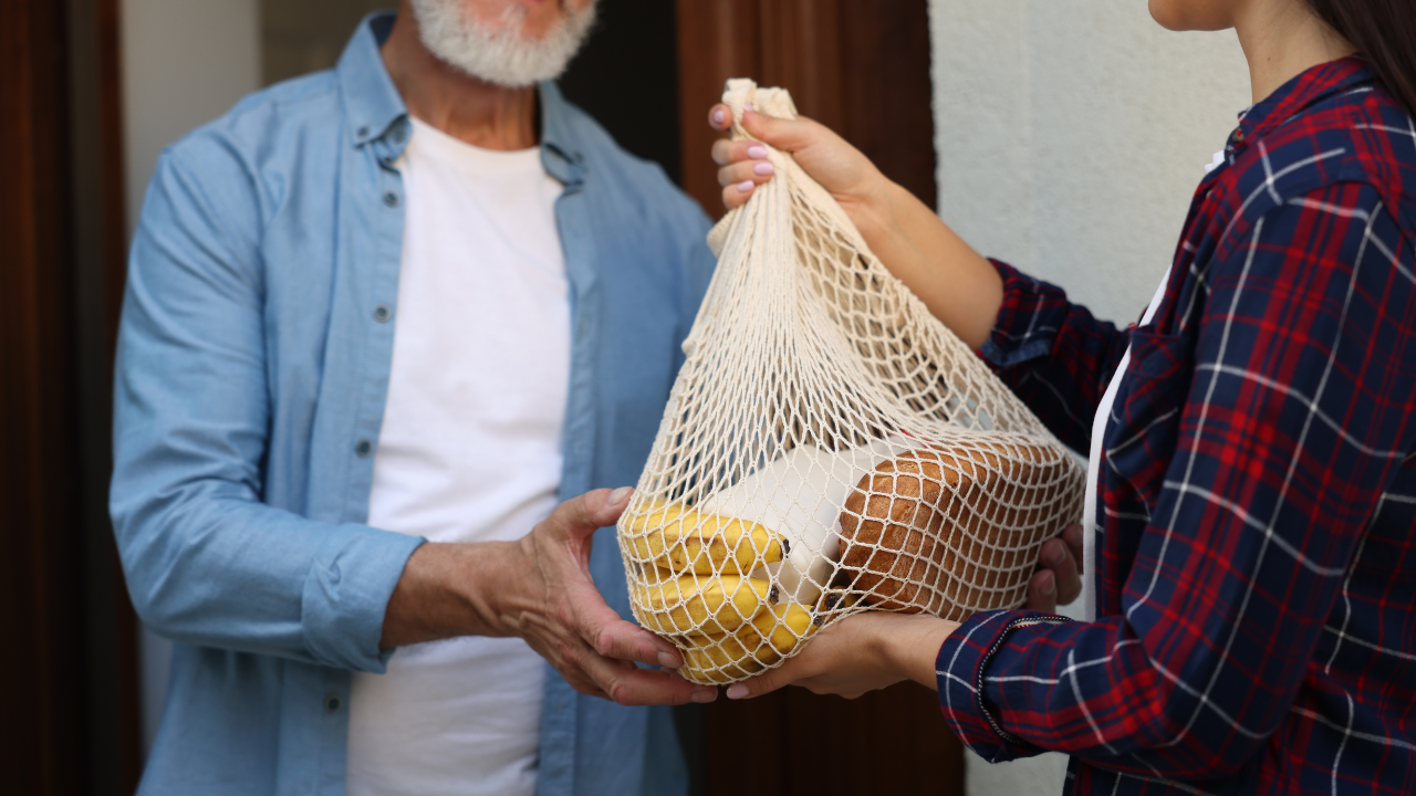 person delivering groceries to elderly man
