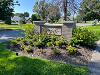 a sign outside of a neighborhood surrounded by landscaping